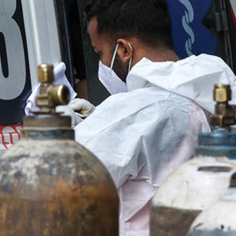 A health worker next to oxygen cylinders taking information from a COVID-19 coronavirus positive person, inside the ambulance, at MMC hospital in Guwahati, Assam, India on 25 May 2021. (David Talukdar/NurPhoto via Getty Images)