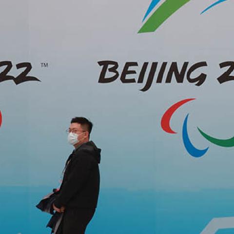 A Chinese man wears a protective mask as he walks in front the logos of the 2022 Beijing Winter Olympics at National Aquatics Centre on April 9, 2021 in Beijing, China. (Photo by Lintao Zhang/Getty Images)