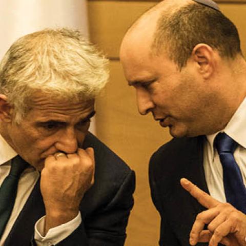 Naftali Bennett (R), leader of the Yamina right-wing alliance, speaks with Yair Lapid, leader of the Yesh Atid opposition centrist party attend first cabinet meeting at the Israeli Parliament (Photo by Ilia Yefimovich/picture alliance via Getty Images)