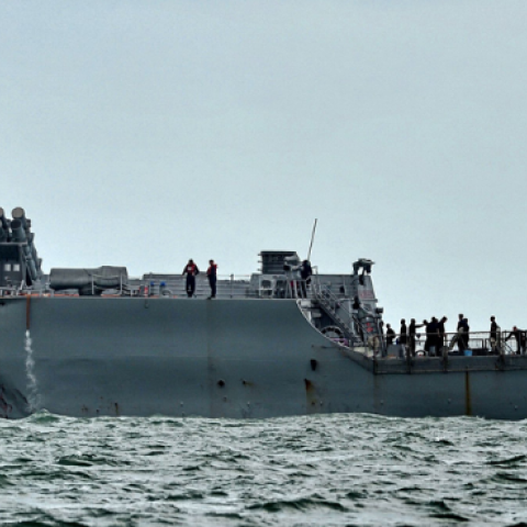 A general view shows the guided-missile destroyer USS John S. McCain with a hole on its left portside after a collision with oil tanker, outside Changi naval base in Singapore on August 21, 2017. (ROSLAN RAHMAN/AFP via Getty Images)