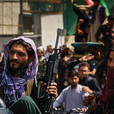 Afghans march down the street carrying banners and the flag of the Islamic Republic of Afghanistan, despite the presence of Taliban fighters around them, in Kabul, Afghanistan, Thursday, Aug. 19, 2021 (MARCUS YAM / LOS ANGELES TIMES)
