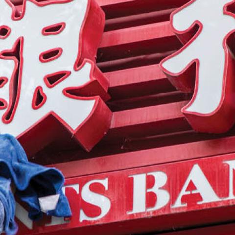 A worker cleans up the signage of a bank storefront on October 19, 2020 in Shanghai, China. (VCG/VCG via Getty Images)