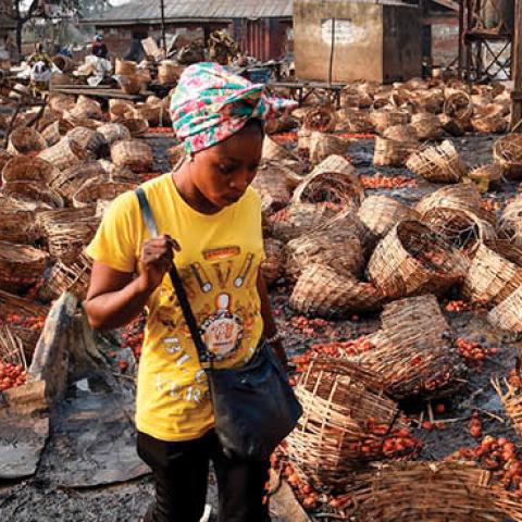 A woman walks among baskets full of tomatoes vandalized after deadly ethnic clashes between the northern Fulani and southern Yoruba traders at Shasha Market in Ibadan, southwest Nigeria, on February 15, 2021. (Pius Utomi Ekpei/AFP via Getty Images)