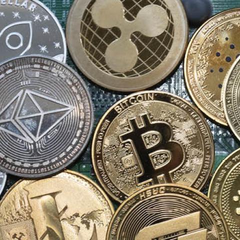 Metal coins imprinted with cryptocurrency logos placed on a computer board. (Ulrich Baumgarten/Getty Images)