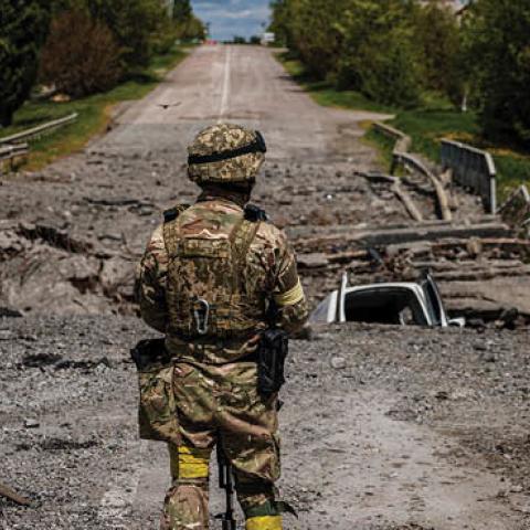 A soldier of the Kraken Ukrainian special forces unit observes the area at a destroyed bridge north of Kharkiv, on May 16, 2022. (Photo by Dimitar Dilkoff/ AFP)
