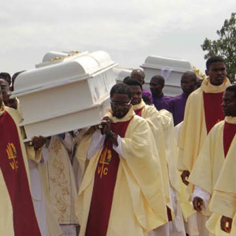 Clergymen carry white coffins containing the bodies of priests allegedly killed by Fulani herdsmen, for burial at Ayati-Ikpayongo in Gwer East district of Benue State, north-central Nigeria on May 22, 2018. (Emmy Ibu/AFP via Getty Images)