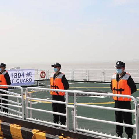 Officers of the China Coast Guard stand on deck as they set sail in the North Pacific Ocean from Shanghai, on July 30, 2021. (Photo by Xinhua via Getty Images)