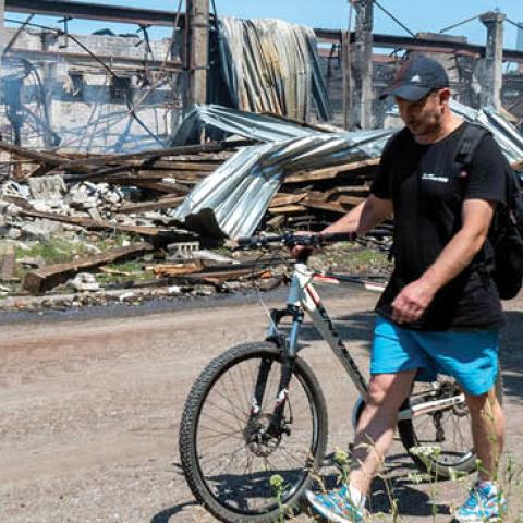 A man pushes a bicycle as he walks past a building of Mashgidroprivod plant, which was destroyed by a Russian missile attack in Kharkiv on June 29, 2022, amid the Russian invasion of Ukraine. (Photo by Sergey Bobok/AFP via Getty Images)