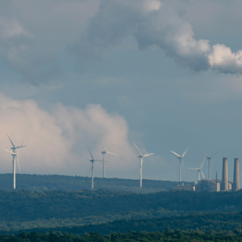 Turbines from the Mount Storm Wind Farm stand in the distance behind the Dominion Mount Storm power station August 22, 2022, in Mount Storm, West Virginia. (Chip Somodevilla/Getty Images)