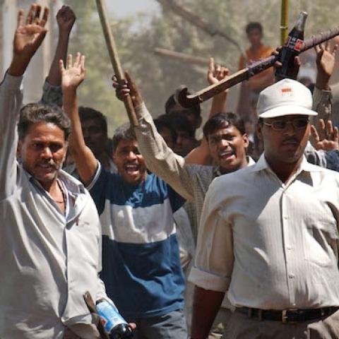 A mob of Hindus wielding swords and sticks back off after Indian Rapid Reaction Force officers stopped them from attacking a small group of Muslims March 1, 2002 in Ahmadabad, India. (Ami Vitale/Getty Images)